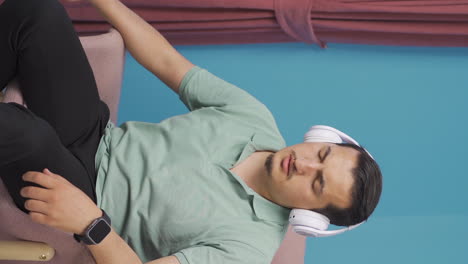 Vertical-video-of-Man-listening-to-music-with-headphones-is-unhappy-and-sad.